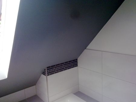 Badezimmer mit dunkel gestrichener Schräge und weißen Fliesen mit Mosaikbordüre